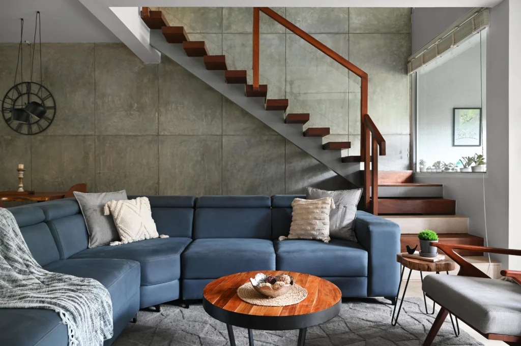 Luxury living room interior featuring exposed white brick wall, wooden shelving, and an elegant sectional sofa
