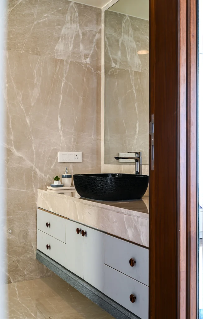 Premium bathroom vanity with marble walls, white cabinetry, and a black textured vessel with a modernized faucet