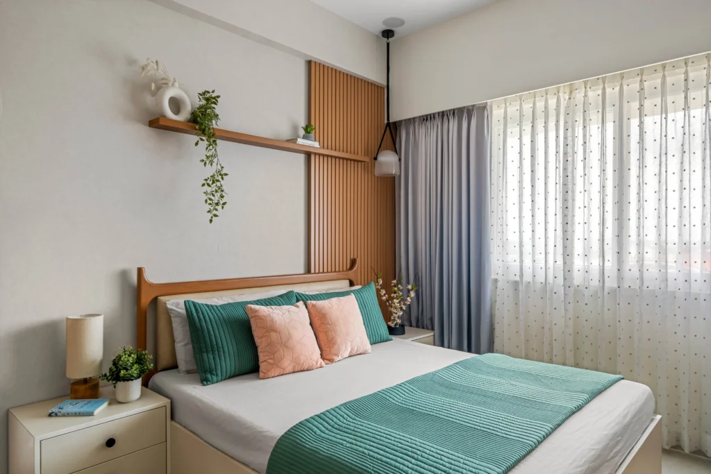 The master bedroom of a 2 BHK apartment in Bangalore, which was meticulously planned and executed to give you a personal sanctuary. With the soft-colored wall, wooden accent, minimal design, and indoor blossoms, this place is a perfect place that welcomes you to relax after a hectic day